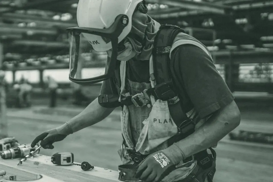 Trabalhador da construção com capacete, protetor facial, máscara, cinto de segurança e luvas